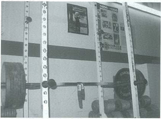 A power rack at Jack King's Gym with heavy dumbbells and IronMind straps